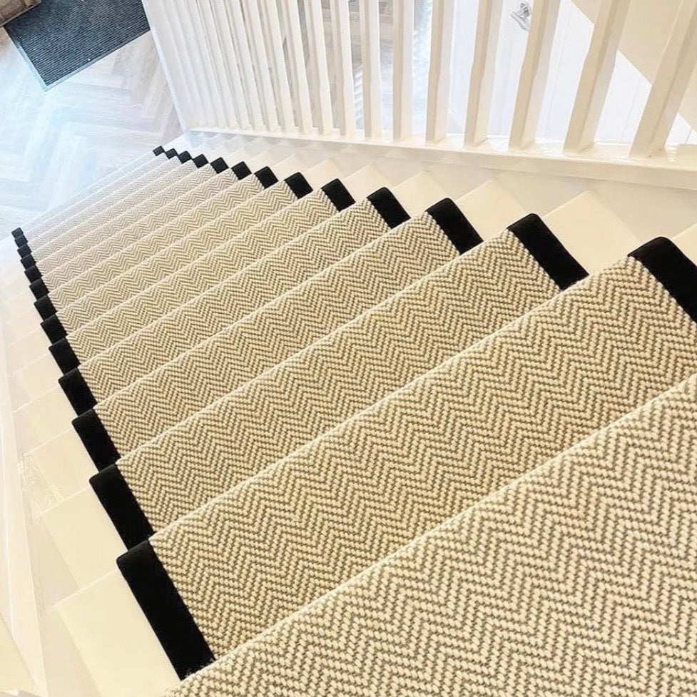 Herringbone wool stair runner with black binding on white painted stairs